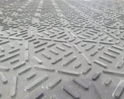 Close-up Image Of A Black Rubber Mat With A Textured Geometric Pattern Consisting Of Short, Raised Lines Arranged In Various Directions. The Lines Create A Complex, Repetitive Design Across The Surface, Typical Of Standard Tread ProtectaMats.
