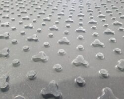 Close-up Image Of A Tactile Paving Surface With Raised, Rounded Bumps. The Bumps Are Arranged In A Regular Pattern On A Flat Background, Designed To Provide Guidance And Warning To Visually Impaired Individuals. Made From ProtectaMats Material, The Sturdy Surface Ensures Reliability And Safety.